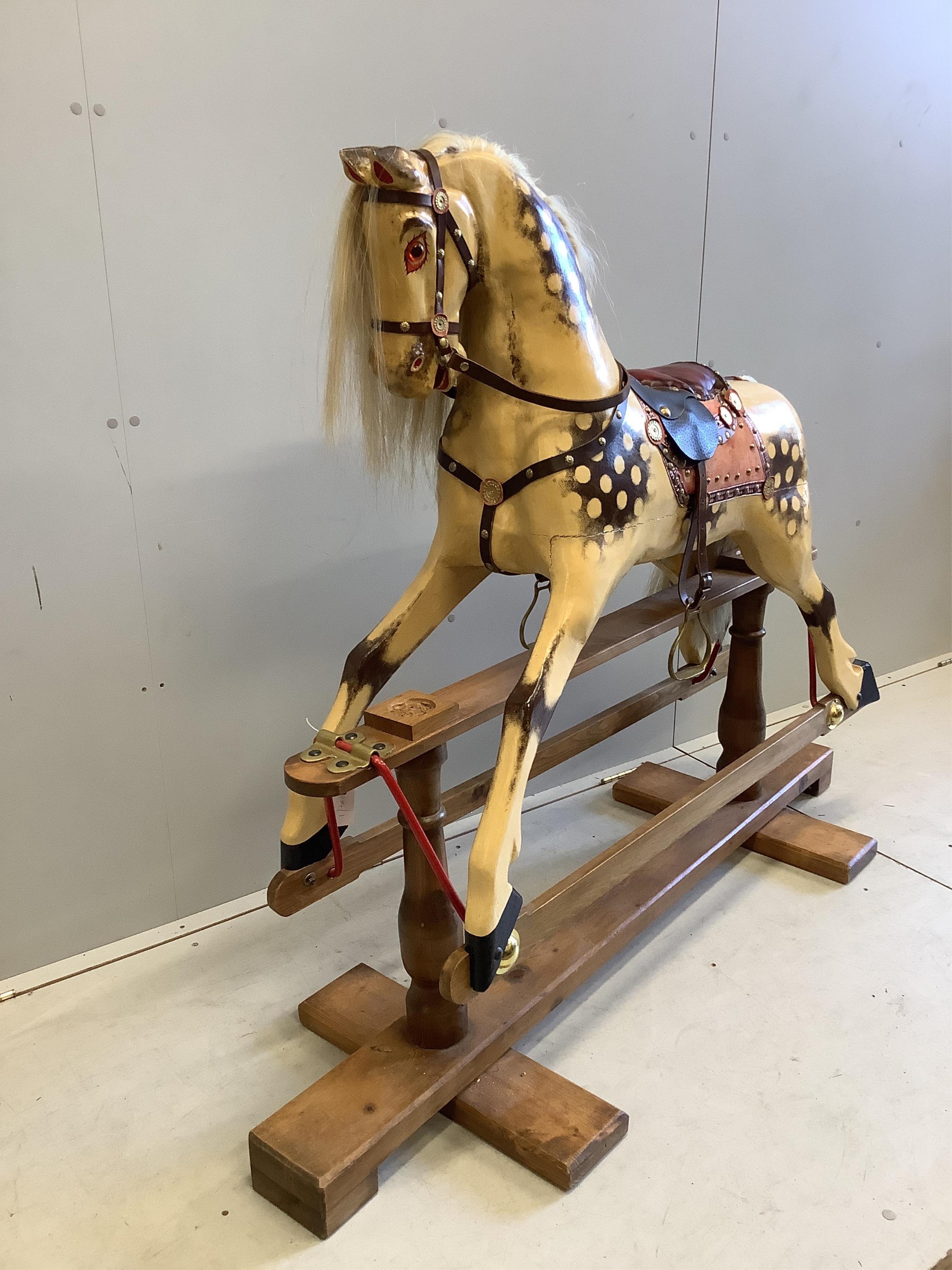 A large carved wooden rocking horse on a pine stand, the body painted in dapple grey, with glass eyes and upholstered leather saddle, height to the top of the head 130cm, length of base 152cm. Condition - fair to good.